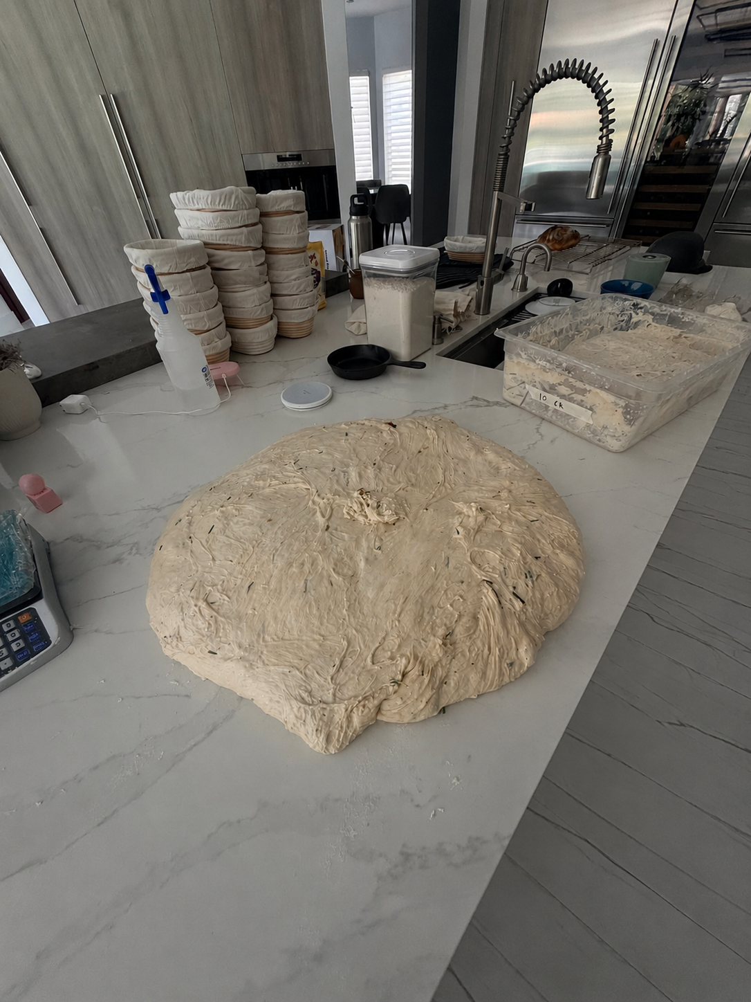 A large batch of sourdough dough being prepared on a kitchen island